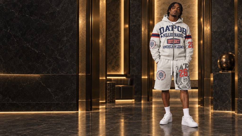 Model wearing the heather-grey DA’POR District hoodie and graphic shorts in a marble lobby